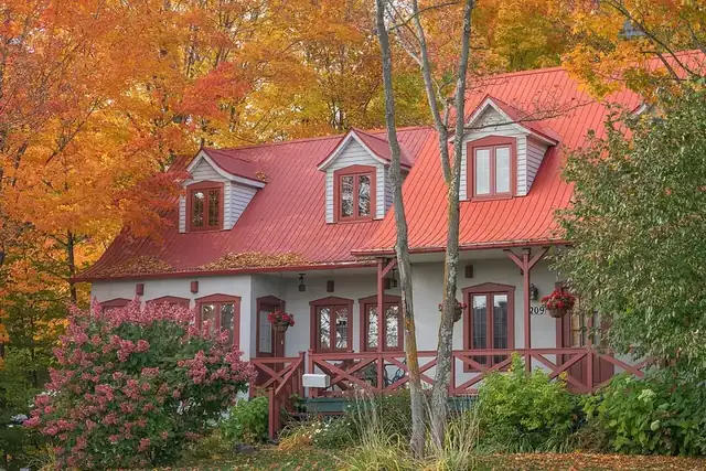 A red-roofed house among orange autumn trees